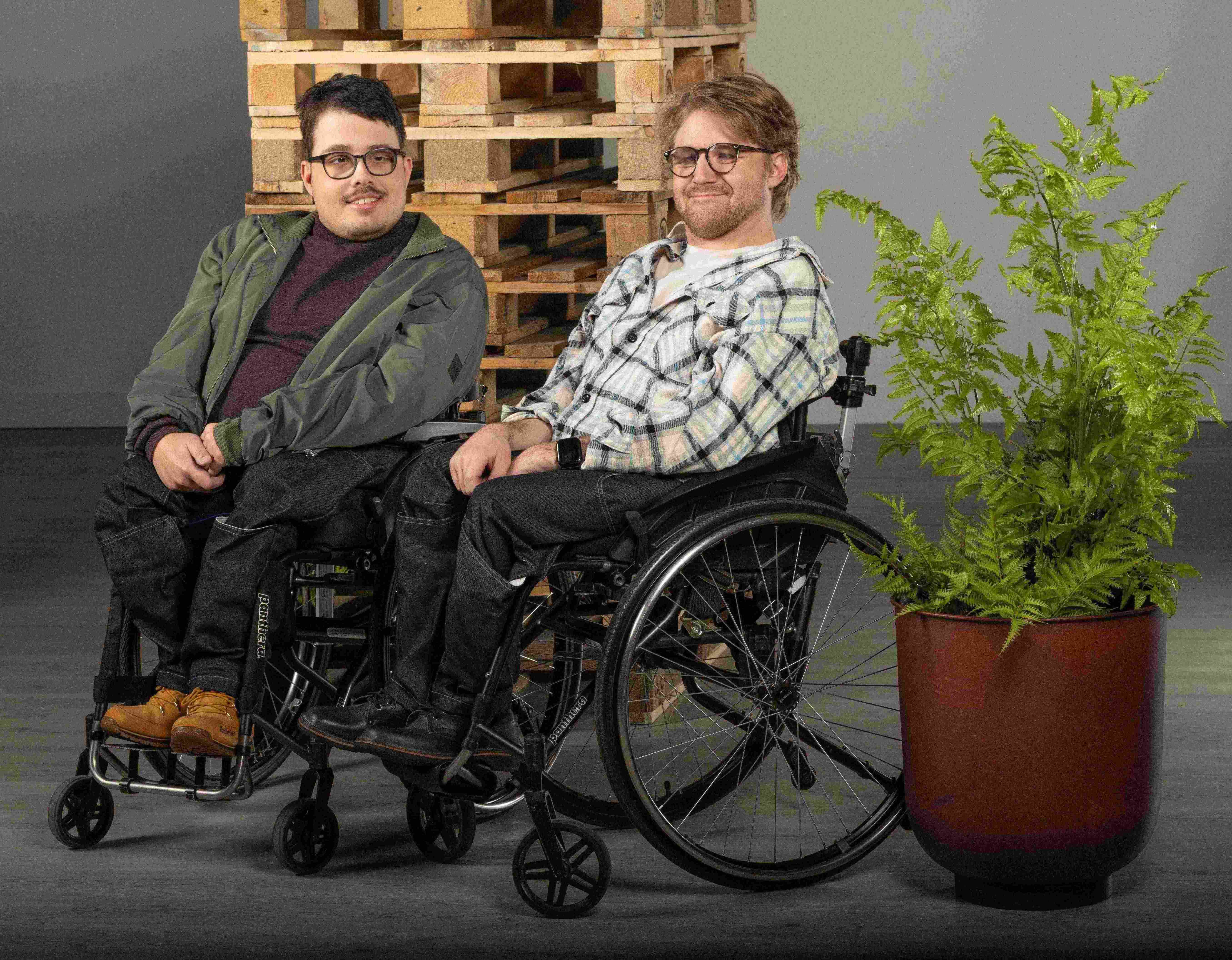 Två manliga modeller som sitter i varsin rullstol. Båda bär jeans från design by björk.